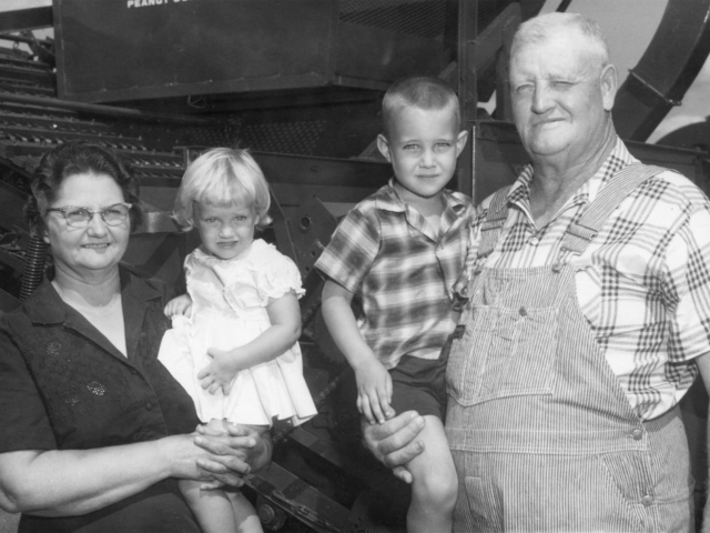 For the 1963 Farm Family award, the OKFB Women designed the contest to honor the state’s pioneer farm families who fought floods, dust bowl days, and the depression in order to remain on the farm. One of the requirements was that the family, or the family’s parents, must have farmed in Oklahoma prior to 1900. The George Lasley family from Eakley was the winner of this special Oklahoma Pioneer Farm Family of the Year award. Both of the Lasleys’ parents originally came to Oklahoma in covered wagons in 1899. In the photo is Mr. and Mrs. Lasley, with the two youngest of their eight grandchildren, Gay and Lloyd.