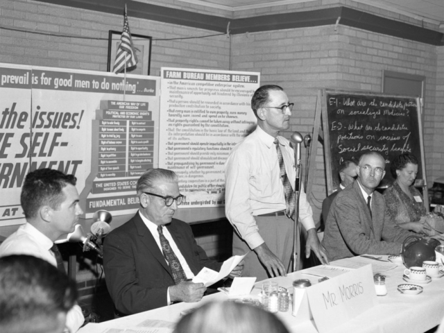 On July 10, 1958, members of Farm Bureau counties in western Oklahoma held this Meet the Candidate forum with two runoff candidates for the democratic nomination for congressman. Congressman Toby Morris (second from left) and challenger Victor Wickersham (second from right) were guests of 100 leaders from 17 western counties of Oklahoma’s Congressional District 6, shown here with OKFB President Lewis H. Munn (at microphone). The candidates were quizzed about their beliefs on 13 different issues and government philosophies in order to compare them against Farm Bureau policy.