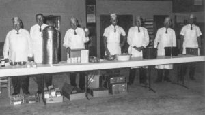 Noble County Farm Bureau Board members dish out the meal at a county annual meeting. Pictured are (left to right) Perry Patch, Homer Main, Oscer Mitchell, Bob Bolay, Walter Hasselwander, Sam Bolay and Alfred Graves, preparing to get the meal underway. Hasselwander was a special insurance agent in the county.