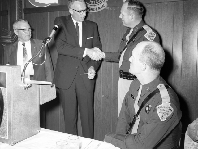 Ted Payne, Oklahoma Farm Bureau Safety Director (second from left), and Col. L.M. Tidd of the American Automobile Association (left), thanks Trooper Bill Price (second from right) and the Oklahoma Highway Patrol for being a part of the “Learn and Live” program just before the show winners were presented. The 1968 program involved five high schools located in central Oklahoma, including schools in Guthrie, Chickasha, Moore, Shawnee and Putnam City. Teams participated in the quiz-based television show by answering questions taken from the Oklahoma traffic code.