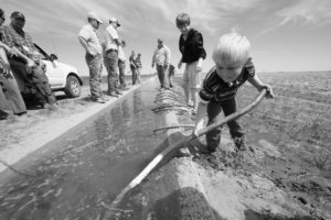 Here, a young Ryan Taylor of Payne County tries his hand at setting a siphon tube in the Lugert-Altus Irrigation District as part of a 2011 OKFB Young Farmers & Ranchers tour.