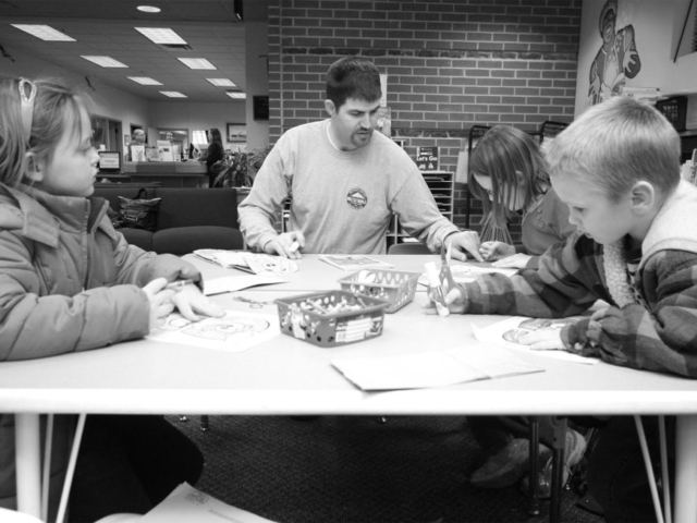 In this January 2012 photo, Major County Farm Bureau Young Farmers & Ranchers member Clint Wilcox (center) helps local children color a farm-themed picture at a local library. County YF&R members also read agricultural books, played farm-themed games and prepared a snack for local grade-school students to help them understand the importance of agriculture in their local community of Fairview and beyond.