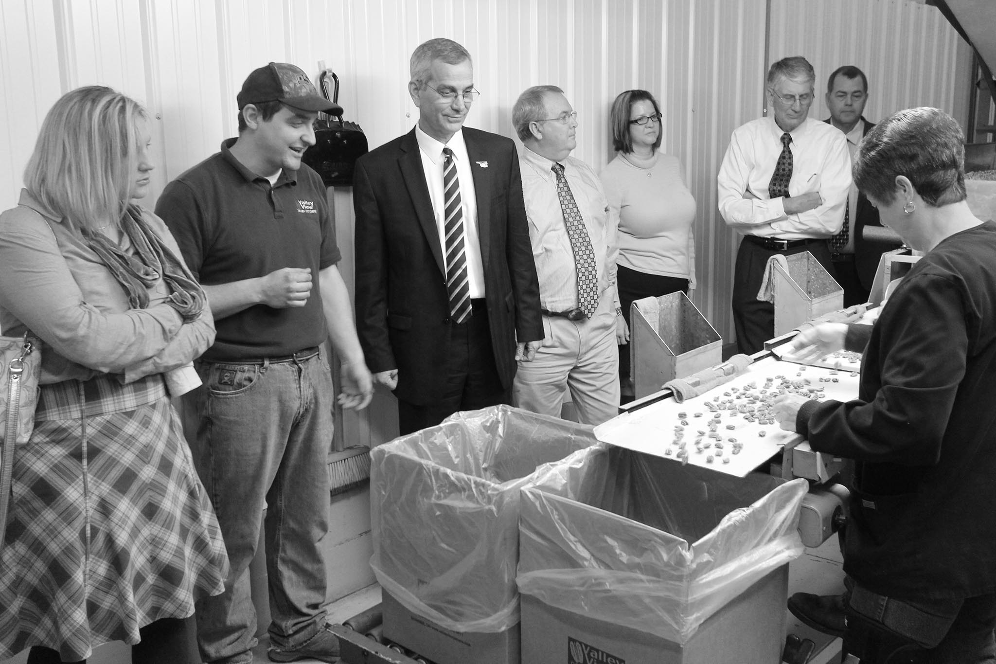 Oklahoma Farm Bureau member Josh Grundmann (second from left) shares the process of cleaning and shelling pecans with the Oklahoma State Board of Agriculture during a tour in 2013. The Grundmann family hosted the group at their business, Valley View Pecans near Earlsboro, to help educate board members about the pecan industry and issues pecan producers and processors face.